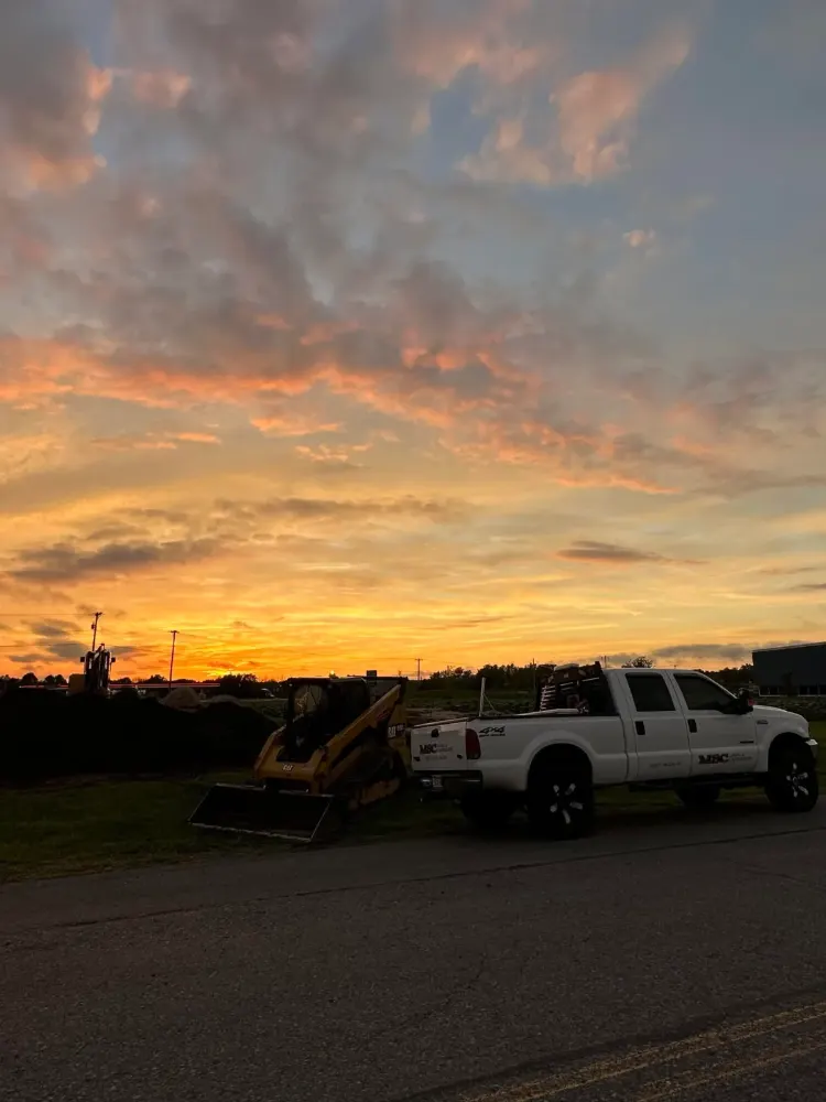 The MSC pickup and a CAT track loader at a job site at sunset